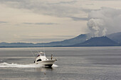 Motor boat in front of smoking volcano, Rabaul, New Britain, Papua New Guinea, Oceania