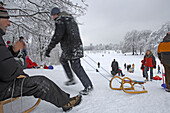 Menschen fahren Schlitten, Wintertag im Englischen Garten, München, Bayern, Deutschland