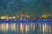 People enjoying themselves at beer garden Seehaus at Kleinhesseloher See in the evening, English Garden, Munich, Bavaria, Germany