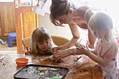 Mother baking with two three year old girls.