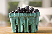 Fruit. Riverwoods, Illinois. Green box of ripe blueberries in kitchen, on wooden board