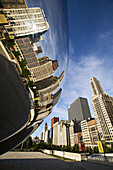 Illinois. Chicago. Cloud Gate sculpture in Millennium Park in early morning, plaza around Bean, stainless steel design, buildings along Michigan Avenue reflected