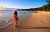 Woman walking on desert beach at sunset. Praslin Island. Seychelles.