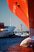 Tugboat and container ship framed by bow of boat in foreground