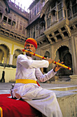 Musician playing at the courtyard of an old palace. India