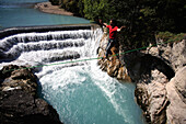 Junger Mann balanciert auf einem Seil über ein Fluß, Füssen, Bayern, Deutschland