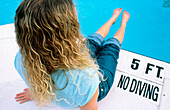 Woman sitting by swimming pool