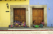 Mayan women selling handicrafts at Spanish colonial doorways. Antigua Guatemala. Guatemala