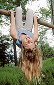 girl hanging from tree branch