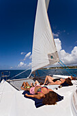 Women sunbathing on a catamaran, West Coast, Barbados, Caribbean