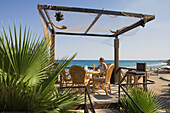 Woman sitting on the terrace of a cafe, restaurant, Bogaz, fishing port, North Cyprus, Cyprus