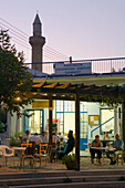 Eine Gruppe Menschen und ein Priester in einem Café, Kafenion, Moschee im Hintergrund, Kalavasos, bei Lemesos, bei Limassol, Südzypern, Zypern