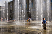 Children playing in the trick fountains and water gardens in front of the House of Parliament on Parliament Square, Bundeshaus, Bundesplatz, Old City of Berne, Berne, Switzerland