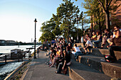People relaxing on the steps of the promenade, River Rhine, Riviera Klein-Basel, Basel, Switzerland