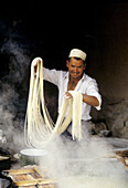 Making noodles in a small food stall on the Camel Market of Kashgar, Xingjang Province. China