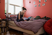 A young woman 20 years old sitting in her room working on university homework
