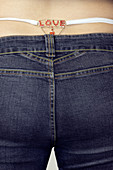 Woman with thong marked Love showing from jeans