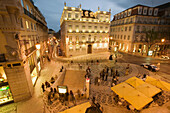 Cafes, traffic and pedestrians on Rua Garrett in the Chiado district at night from above. Lisbon. Portugal