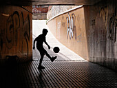 Boy playing with ball in underground pass