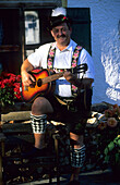 Mathias Pongraz playing the guitar wearing a traditional Bavarian costume, Bavaria, Germany