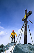 Mountaineer at summit cross, Grossglockner, Hohe Tauern National Park, Austria