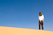 Woman inspecting, looking at a sand dune, desert, United Arab Emirates
