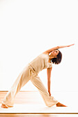 Frau mittleren Alters macht Yoga (Dreieck,Trikonasana), Yogastudio in Linz, Österreich