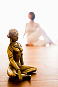 Mid adult woman practising yoga, Buddha figurine in foreground (Half Spinal Twist), yoga studio at Linz, Austria