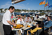 Waiter Serving Paella at La Caracola Restaurant, Portocolom, Mallorca, Balearic Islands, Spain