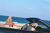 couple in a convertible relaxing at the beach
