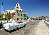 Wedding party on wheels, new bride atop white convertible in Havana. Cuba