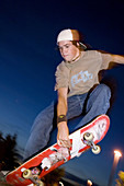 Teenage boy skateboarding at dusk.