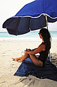 Woman sitting under an umbrella on Saline Beach, St. Barts