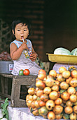 Young baby girl in a fruit market. Bali, Indonesia