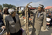 an old uygur sell a braid of garlics at kashgar sundy market. kashgar. xinjiang. china. asia.