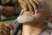 Barber cut the moustache of a uigur man. Kashgar city. Xinjiang province. China. Asia.