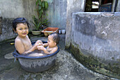 a girl with her younger sister have a bath in a plastic basin. yogyakarta. yogyakarta special region. indonesia. asia.