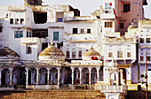 White and blue painted building at the base of the holy lake on the Ghat steps in India Pushkar at dusk. Asia.