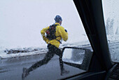 Looking through wet window at man running in the rain on Donner Summit, California. USA