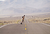 A man skateboarding on a desert road near Lone Pine, California. USA
