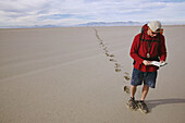 A man using a map and compass while backpacking acrossing the Bonneville Salt Flats in Utah.