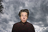 Middle-age man posing in front of a cloudy sky.