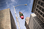 Christmas decorations attached to a light pole on a city street.