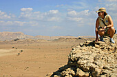 Woman on a rock looking out over Fossil Valley, Buraimi, Oman.