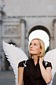 Mid adult woman wearing angel wings near Victory Gate, Munich, Bavaria, Germany