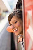 Junge Frau schaut aus einem Fenster von einem fahrenem Zug