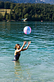 Eine junge Frauen spielt im Walchensee mit einem Ball, Oberbayern, Bayern, Deutschland