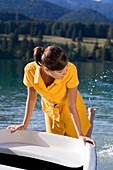 Young woman splashing with feet in lake Walchensee, Bavaria, Germany