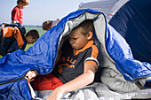 Junge (10-11 Jahre) in einem Schlafsack