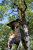 Young couple sitting on raised blind, Vorderriss, Lenggries, Bavaria, Germany